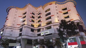 Un bâtiment moderne à la façade incurvée, doté de nombreux balcons et d’une enseigne indiquant « Treebo Trust Metropolis ».