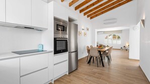 A modern kitchen with white cabinetry, a built-in oven, and a stainless steel refrigerator. - Villa Amanecer - Plus (Calpe)
