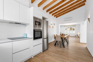 Eine moderne Küche mit weißen Schränken, einem eingebauten Backofen und einem Edelstahl-Kühlschrank.
