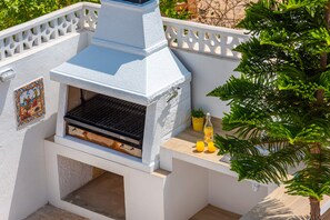 Uma churrasqueira para área externa com exterior branco, uma chaminé e painel de azulejos.