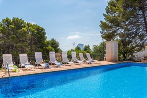 A swimming pool with lounge chairs and a water fountain.