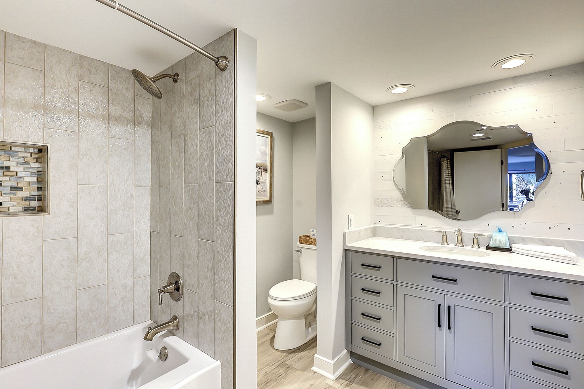 Une salle de bain moderne équipée d’une douche, de toilettes et d’un meuble-lavabo avec des tiroirs et un miroir.