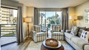 A hotel room with a large window, two armchairs, a sofa, a coffee table, and a floor lamp. - 3123 Villamare:  Beautiful contemporary condo and newly updated, Oceanview (Hilton Head Island)