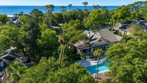 A residential area with a swimming pool, surrounded by lush greenery and a view of the ocean. - 30 W. Beach Lagoon-Golf Course Views, Pool, 2nd row (147 yards) to the ocean (Hilton Head Island)