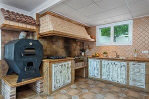 A kitchen with a built-in wood stove, a window, and a tiled backsplash.