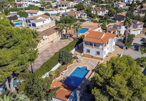 Bairro residencial com várias casas, piscina e jardim bem cuidado.