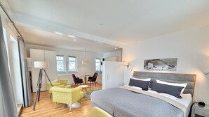 Moderni hotellihuone, jossa on suuri sänky, työpöytä, tuoli ja ruokailutila.