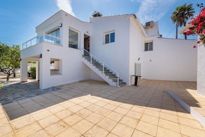 Uma casa moderna de dois andares com escadas, varanda e um pátio com azulejos.