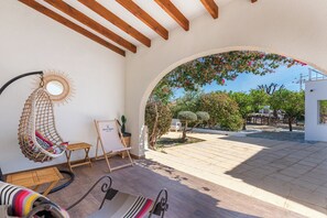 A sunlit patio with a hanging chair, a small table, and a framed artwork.