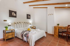 A bedroom with a bed, bedside tables, a desk, and a chair.
