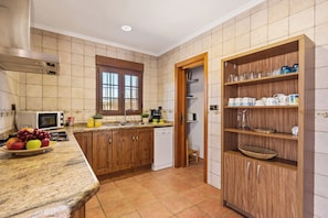 A kitchen with wooden cabinets, a microwave, a sink, and a fruit bowl.