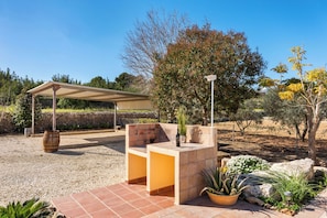 An outdoor seating area with a pergola, a stone table, and potted plants.