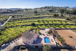 A villa with a swimming pool, surrounded by terraced vineyards and a clear sky.