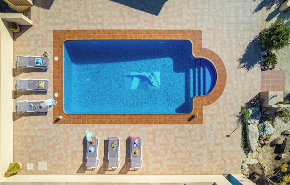An aerial view of a swimming pool with lounge chairs and a sunbathing area.