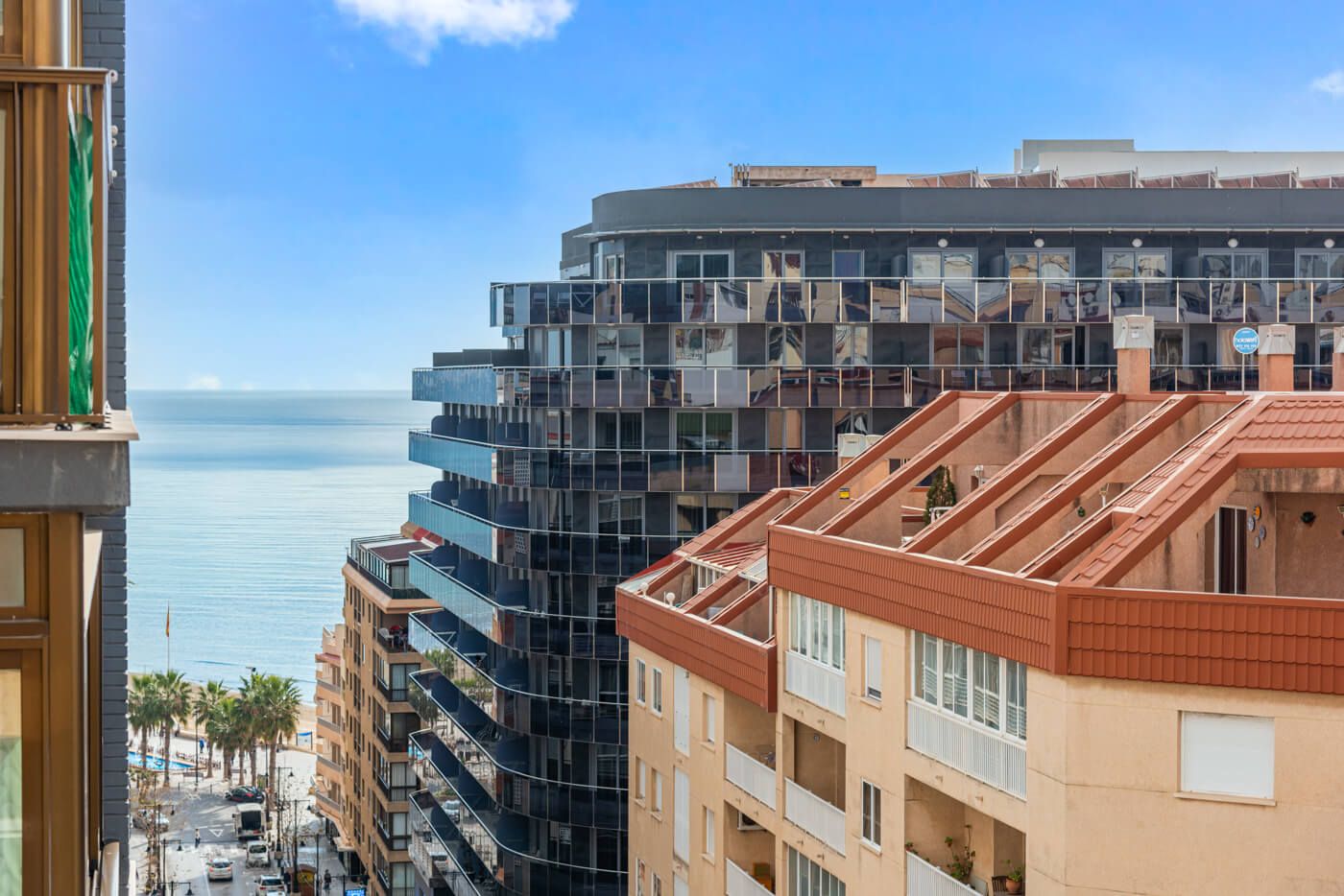 A multi-story building with balconies and a view of the sea.