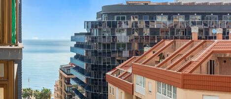 A multi-story building with balconies and a view of the sea.