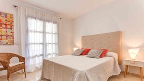 A bedroom with a large bed, a chair, a bedside table, and a wall decoration. - Homo Aura. Villa with private pool in Playa Blanca (Playa Blanca (Yaiza))
