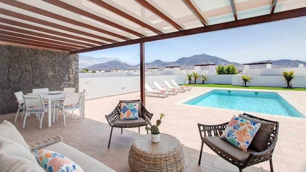 A rooftop terrace with a pool, outdoor seating, and a view of mountains. - Homo Aura. Villa with private pool in Playa Blanca (Playa Blanca (Yaiza))