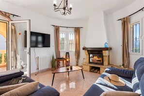 A spacious living room with a fireplace, a flat-screen TV, and comfortable seating.