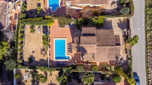 An aerial view of a resort with a swimming pool, sun loungers, and a covered patio area.