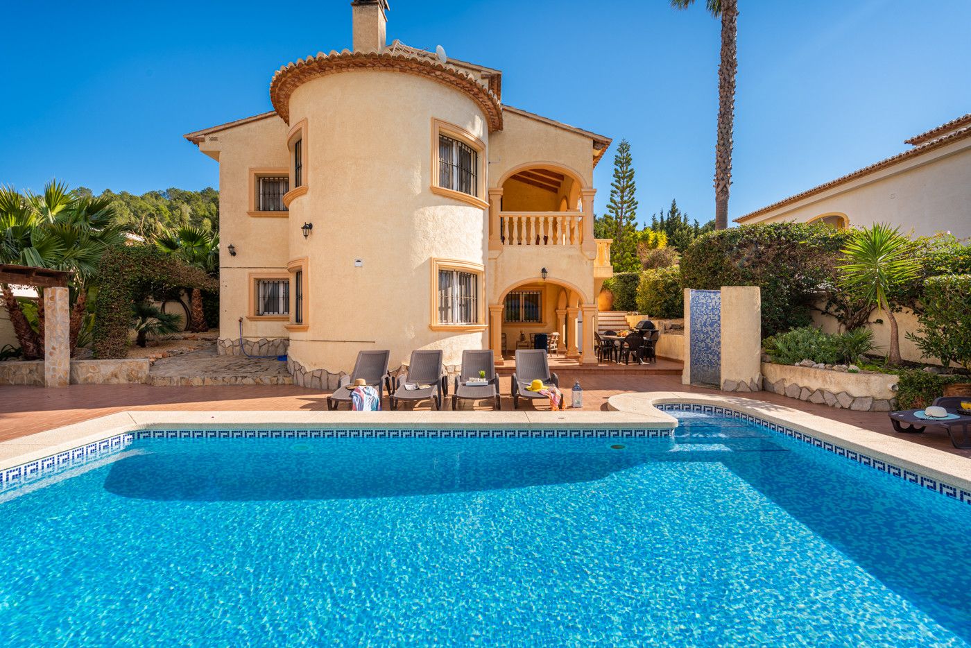 A two-story house with a swimming pool, outdoor seating, and a garden.