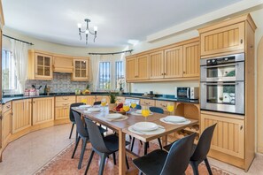 Cozinha moderna com armários de madeira, uma mesa de jantar posta para quatro pessoas e um forno embutido.
