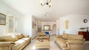 Ett rymligt vardagsrum med två beige soffor, ett soffbord och en takfläkt.