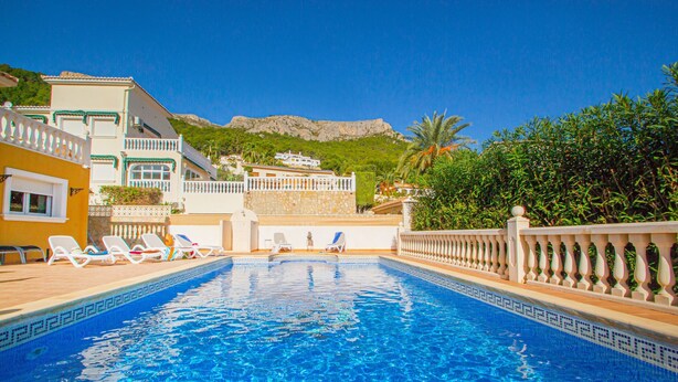 En swimmingpool med solstolar och utsikt över ett berg.