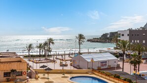 Un hotel sulla spiaggia con piscina, palme e vista sull'oceano.