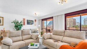 Un soggiorno moderno con due divani beige, un tavolino e un balcone con vista sulla città.
