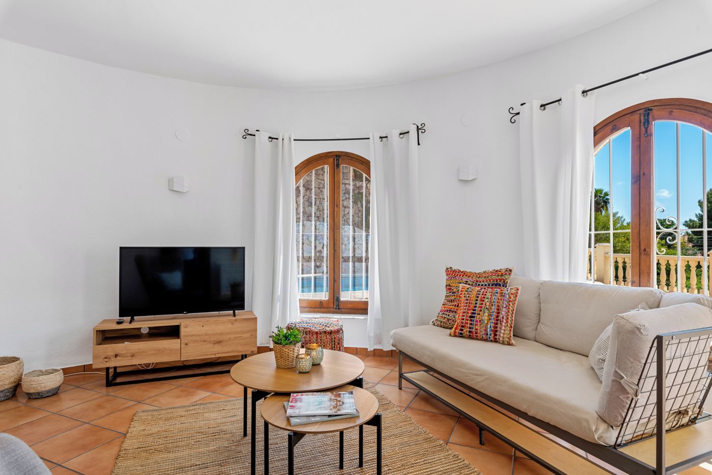 Una sala de estar moderna con un sofá, televisor y una mesita con una revista.