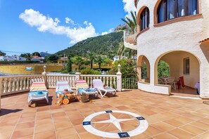 A terrace with sun loungers, a compass, and a view of a mountain.