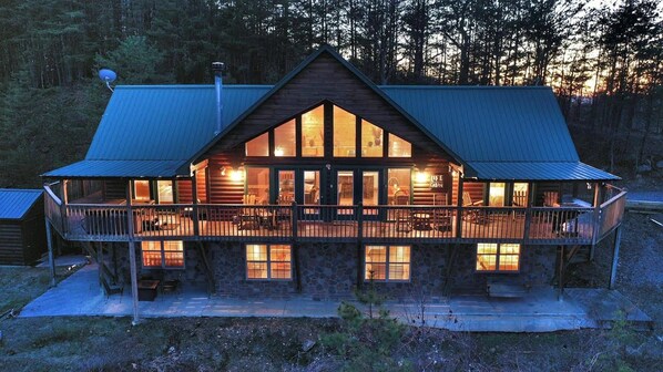 A log cabin with a large deck, multiple windows, and a chimney.