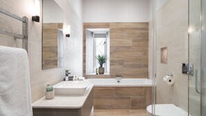Une salle de bain moderne avec un grand miroir, un lavabo, une baignoire et des toilettes.