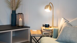 Une pièce chaleureuse avec une petite table en bois, une lampe, une bougie et un vase contenant des plantes séchées.