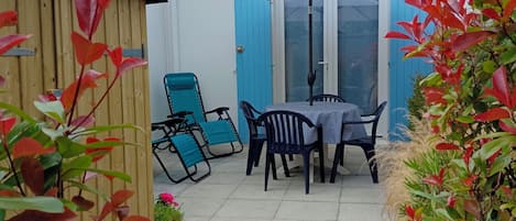 A patio with a table and chairs, a wooden deck, and a blue door.