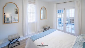 Ein Schlafzimmer mit Bett, Deckenventilator und großen Fenstern.