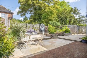 A patio with a table and chairs, surrounded by a brick wall and greenery.