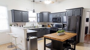 Una cucina moderna con mobili grigi, elettrodomestici in acciaio inossidabile e un'isola in legno con sgabelli.