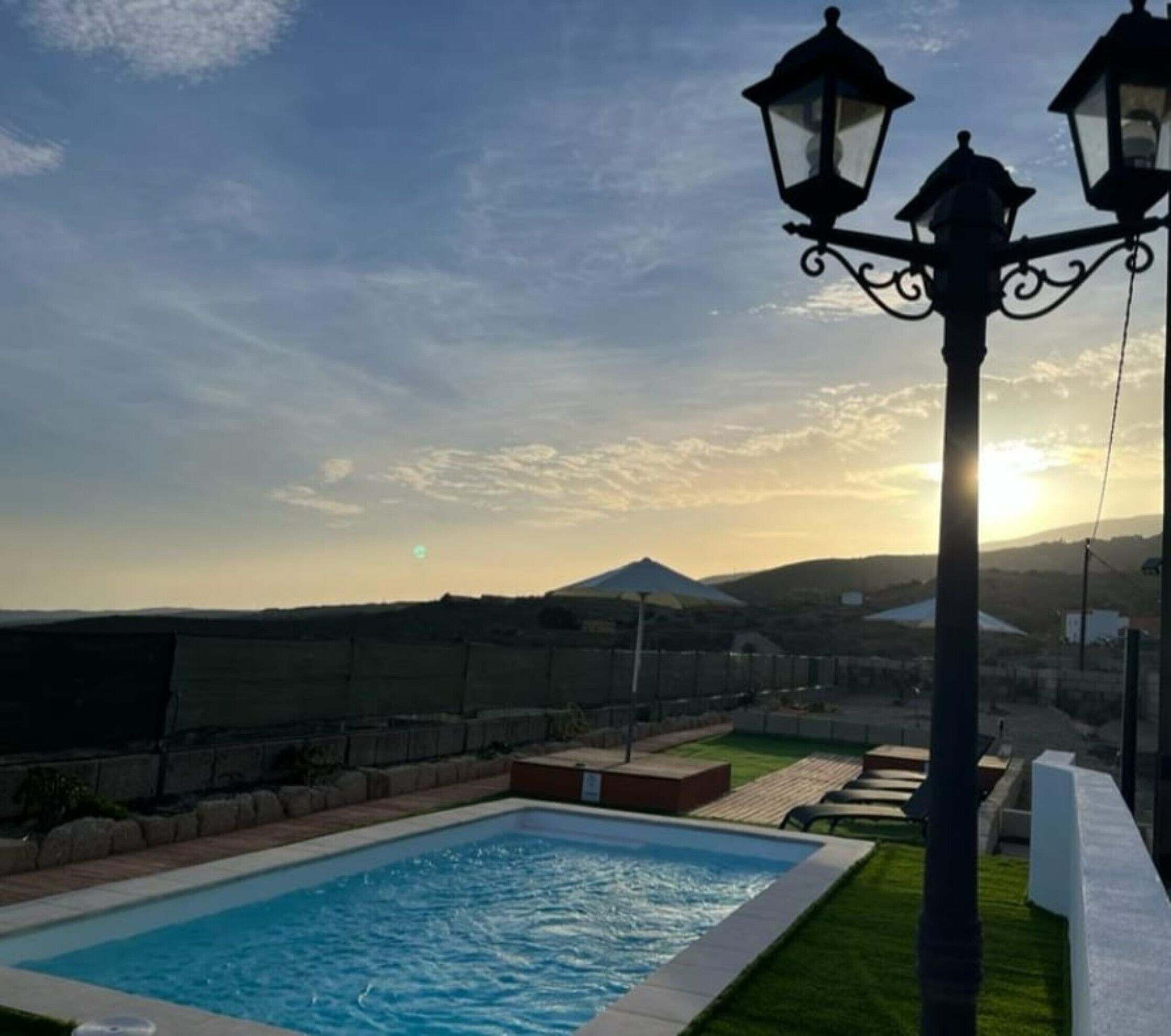 Ein Schwimmbad mit Blick auf einen Berg und einen Sonnenuntergang.