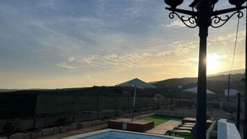 Ein Schwimmbad mit Blick auf einen Berg und einen Sonnenuntergang.