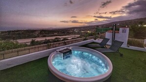 Un bain à remous sur un toit, offrant une vue sur le paysage urbain au crépuscule.