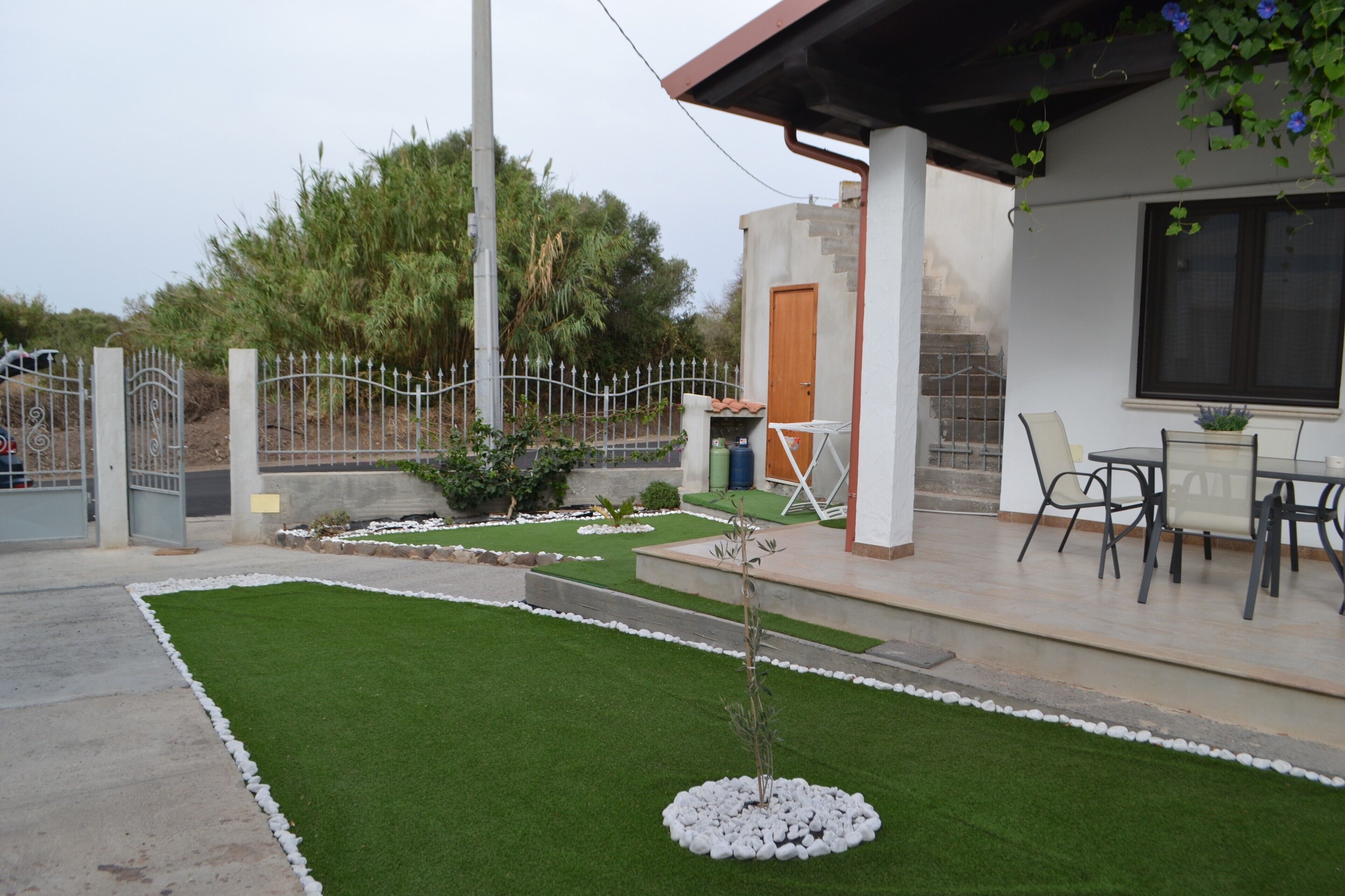 A residential property with a patio, a small lawn, a gate, and a staircase leading to the entrance.