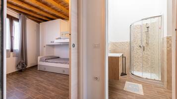 A bedroom with a bunk bed, a small bedside table, and a window with curtains.