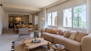 Een ruime woonkamer met een bank, bijzettafeltje en eettafel.