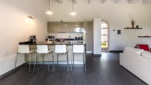 Une cuisine moderne avec des tabourets de bar, un coin repas avec un canapé blanc et une vue sur le salon.