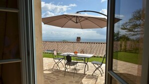 An outdoor patio with a table and chairs, an umbrella, and a stone floor.