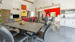 Una cocina moderna con una pared de acento roja, una zona de comedor con una mesa grande y sillas, y una encimera visible.