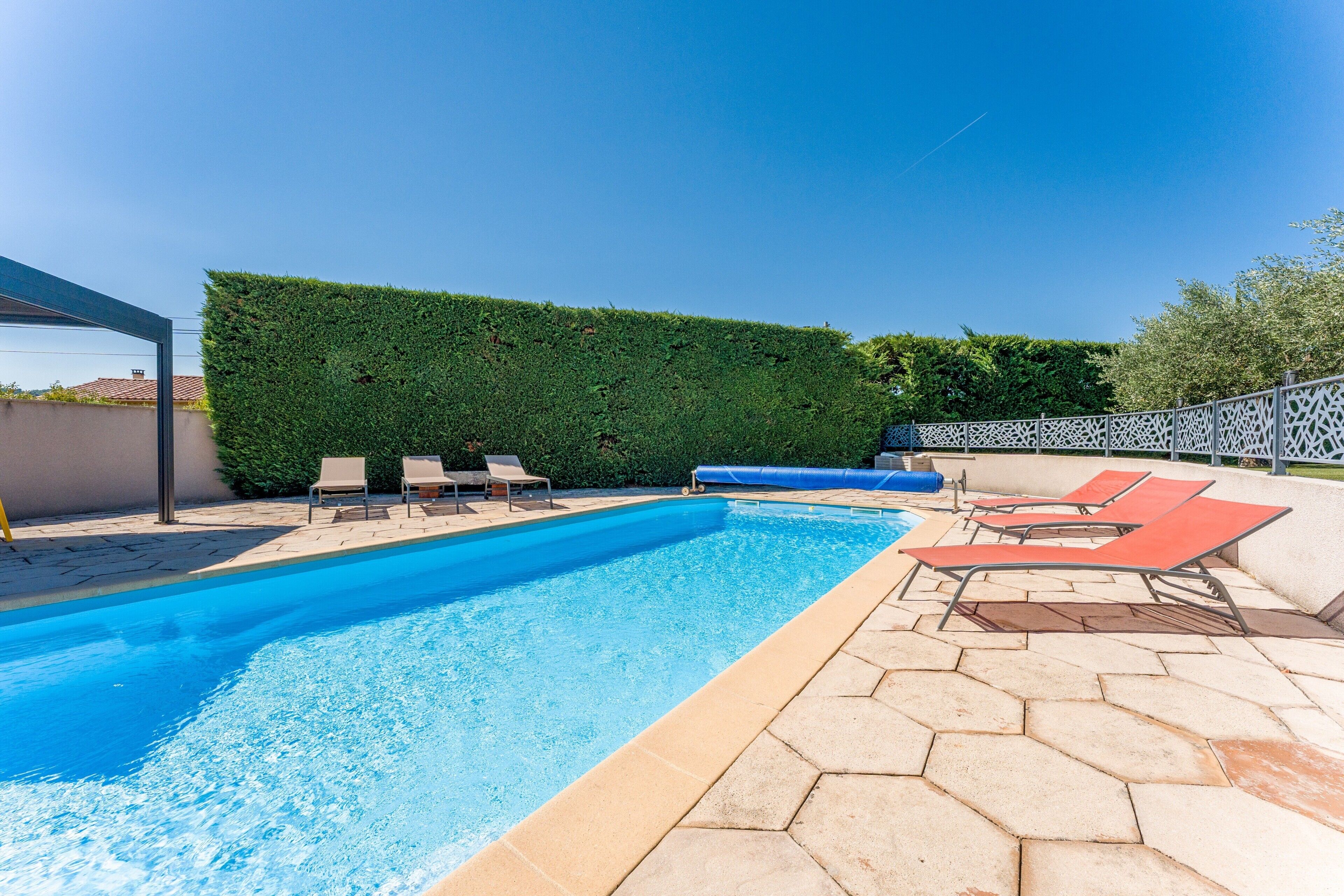 Una piscina amb gandules, un arbust i un pati amb rajoles.