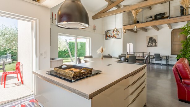 Una cocina moderna con una isla grande, iluminación colgante y vistas al exterior.